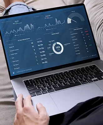A person sitting on the couch with a laptop on their lap, viewing the Databox results for Overall Outdoor Services' CallRail results.