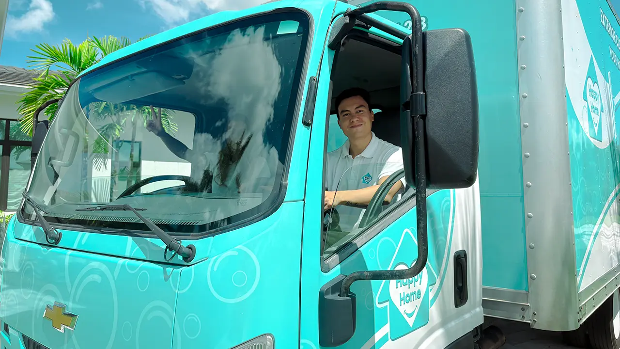 Owner Luis from Happy Home Detailing sitting in the driver's seat of his custom wrapped box truck.